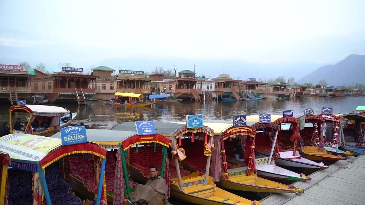 A wooden houseboat on Dal Lake with mountains behind, Kashmir